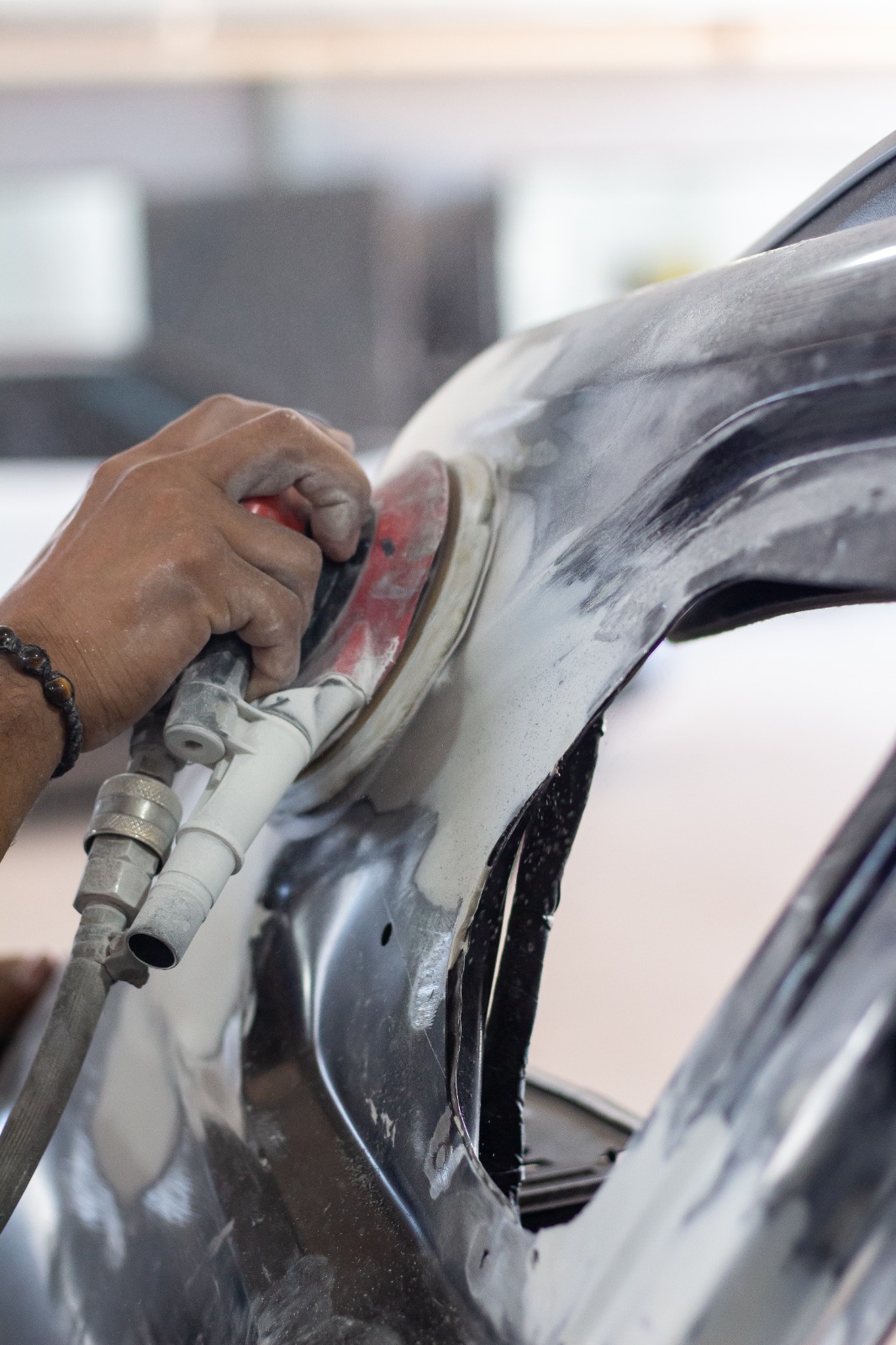 Profissional trabalhando a chapa de um painel com lixadeira orbital